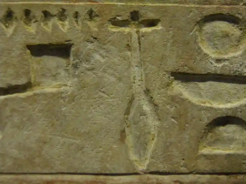 Four-point cross on top of an oblongish symbol on a stele